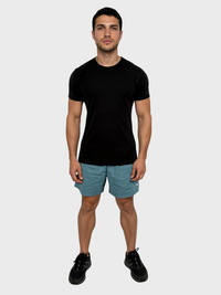Man wearing a black t-shirt and teal shorts on a white background