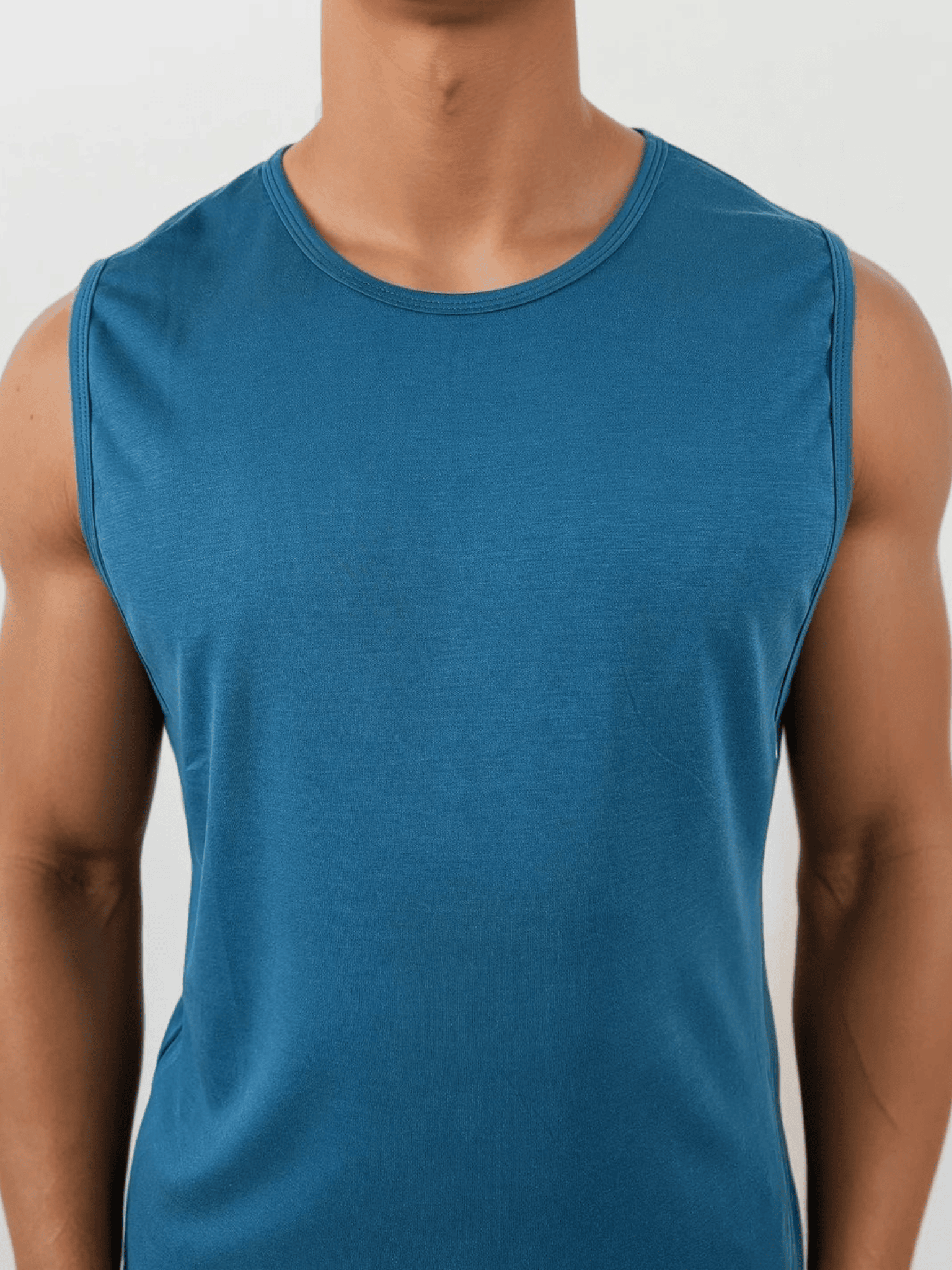 Blue sleeveless shirt worn by a person on a light gray background