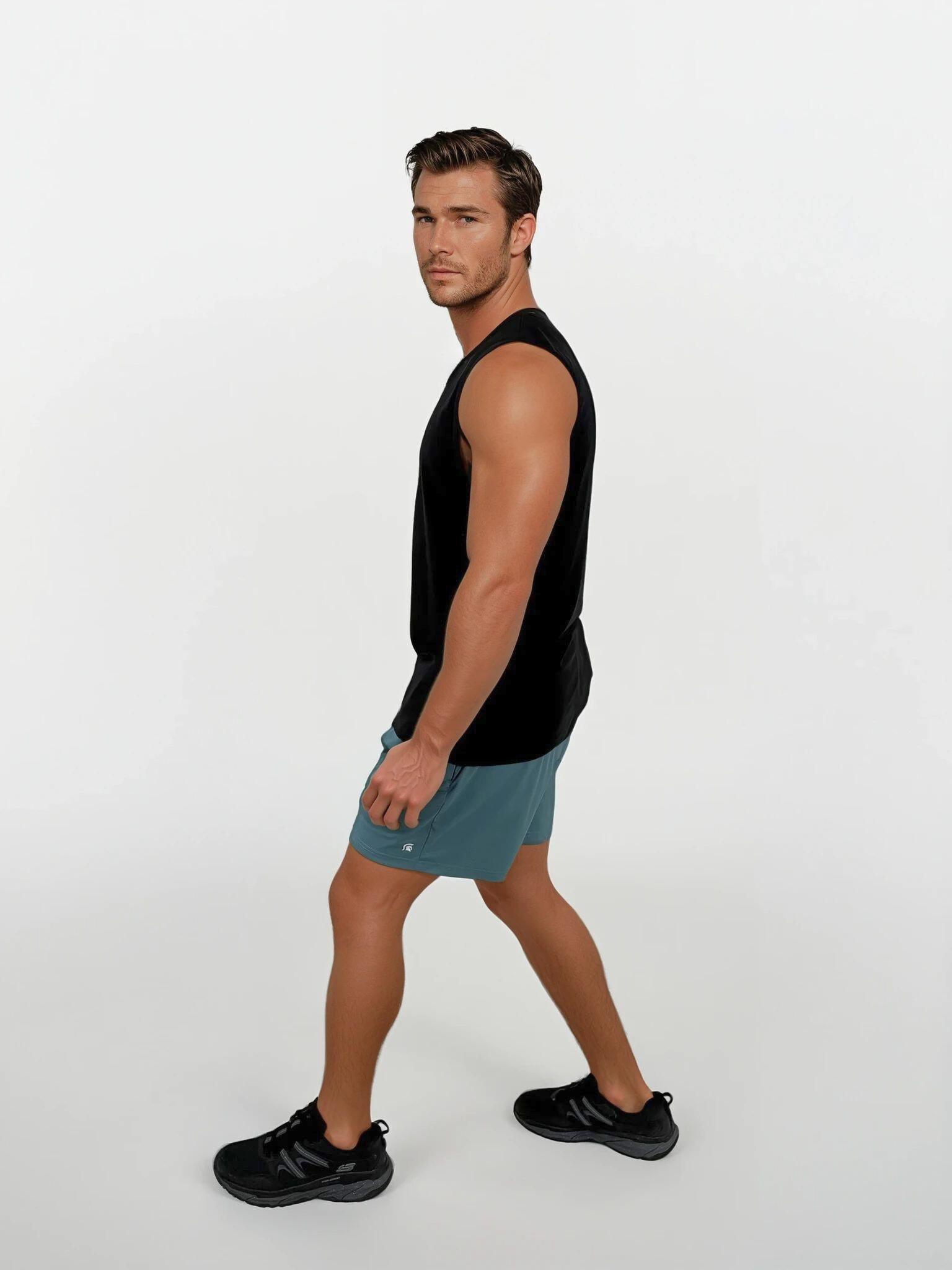 Man wearing a black sleeveless shirt and blue shorts on a white background