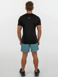 Man wearing a black t-shirt and teal shorts on a white background