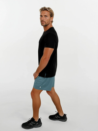 Man wearing a black t-shirt and teal shorts on a white background