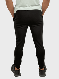 Person wearing black pants and black shoes on a white background