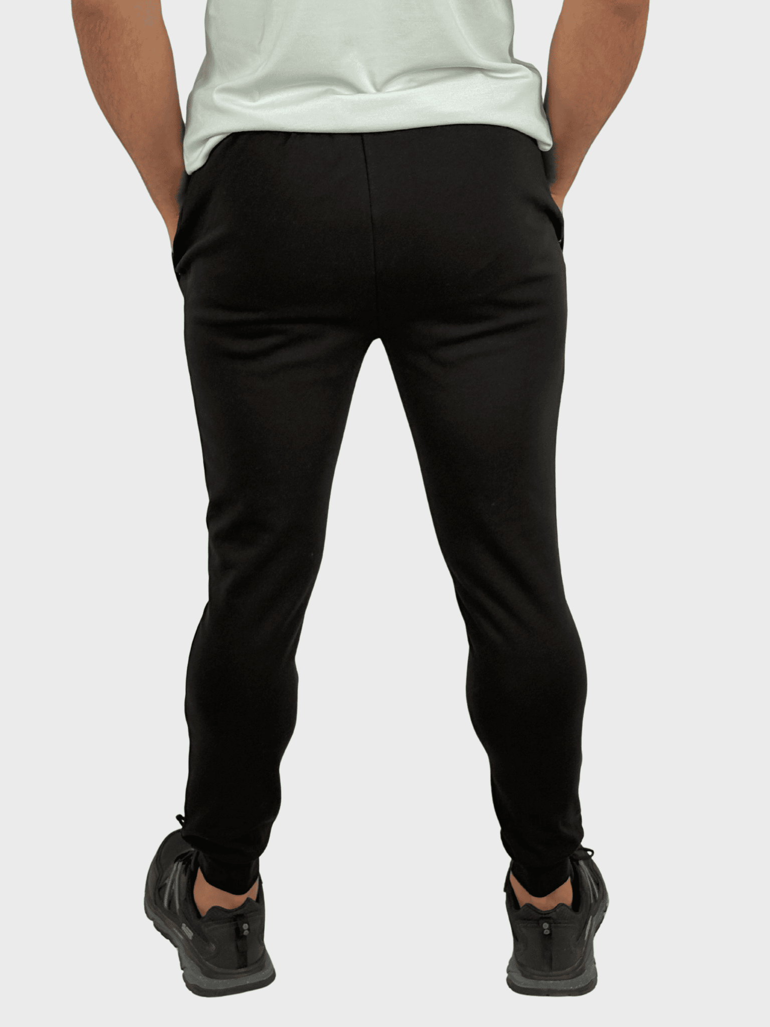 Person wearing black pants and black shoes on a white background