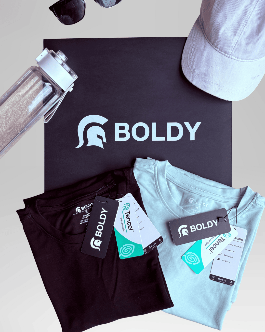 Folded black and light blue t-shirts with 'BOLDY' branding on a black box with the brand logo.