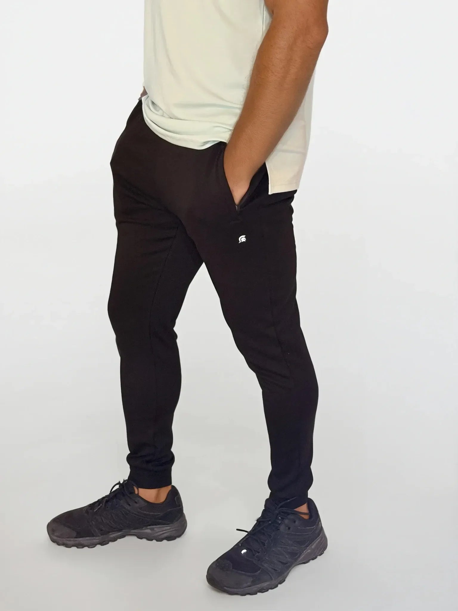 Person wearing black pants and dark shoes on a white background