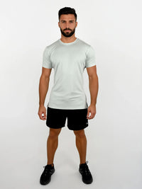 Man wearing a light gray t-shirt and black shorts on a white background