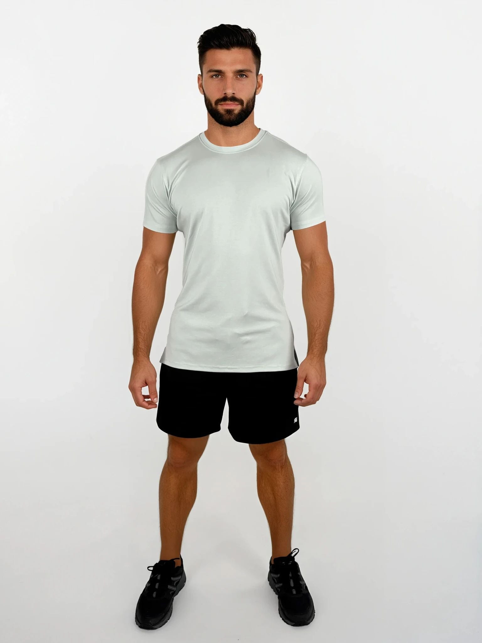 Man wearing a light gray t-shirt and black shorts on a white background