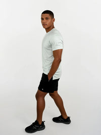 Man wearing a white t-shirt, black shorts, and black shoes on a white background