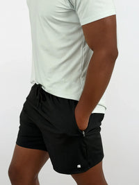 Person wearing black shorts with a small logo on a white background