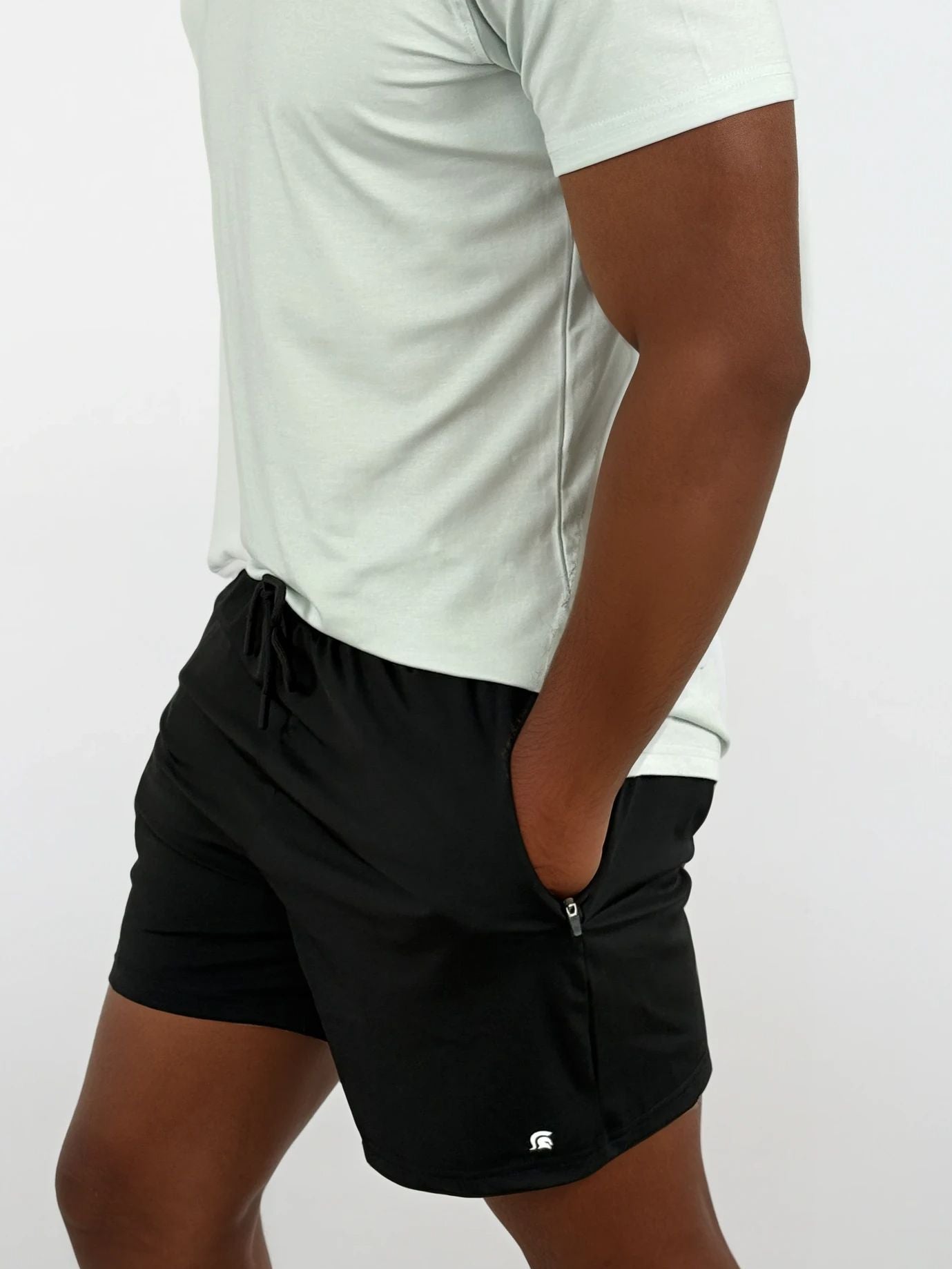 Person wearing black shorts with a small logo on a white background