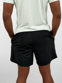 Person wearing black shorts and a light gray t-shirt on a plain background