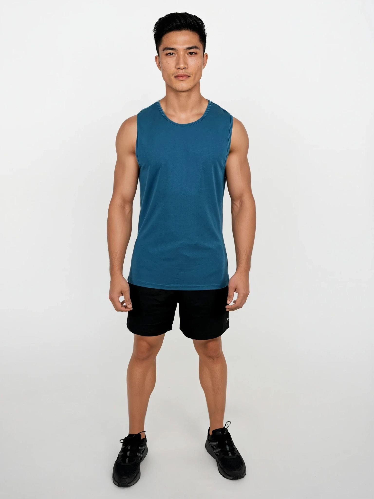 Man wearing a blue sleeveless shirt and black shorts on a white background