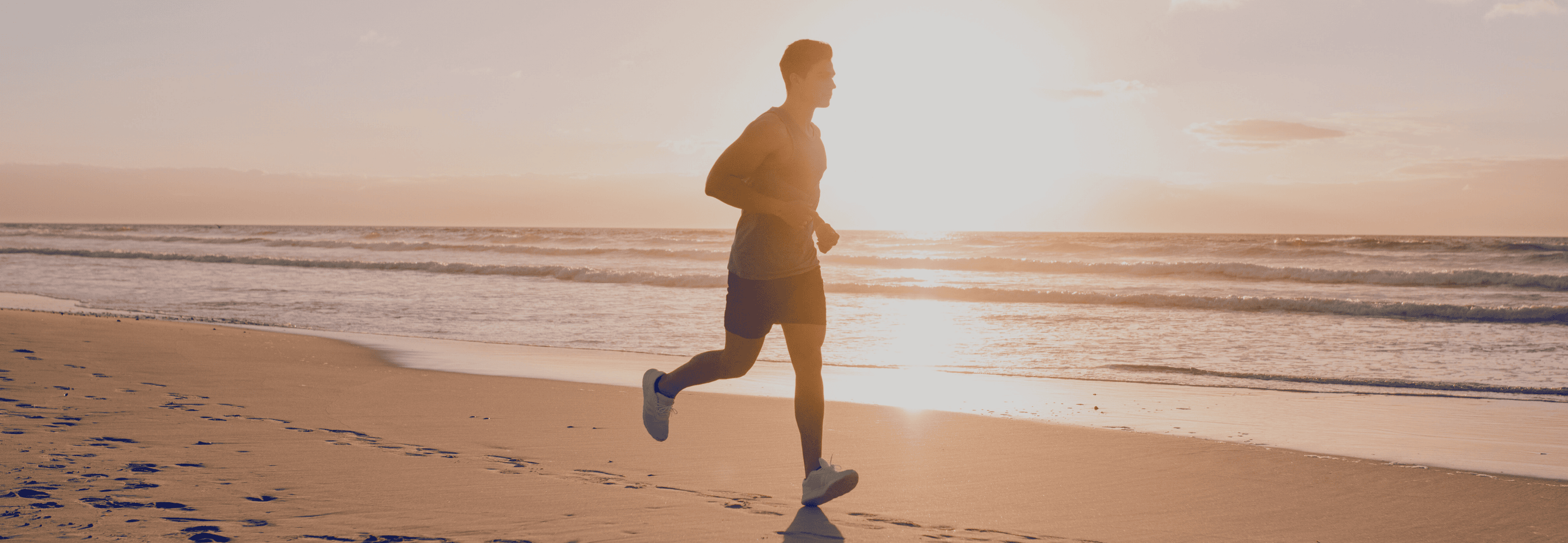 Man running on a beach at sunset